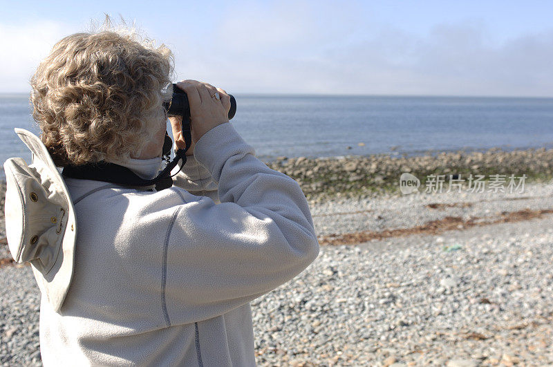 用双筒望远镜俯瞰海滩的女人