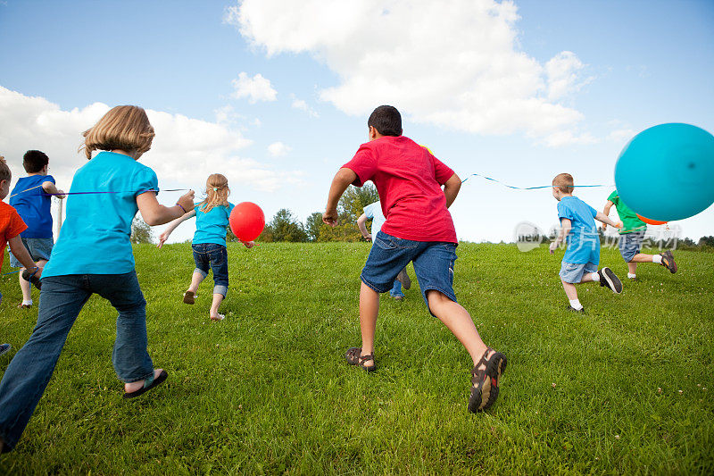 一群快乐的孩子拿着气球奔跑，彩色图像