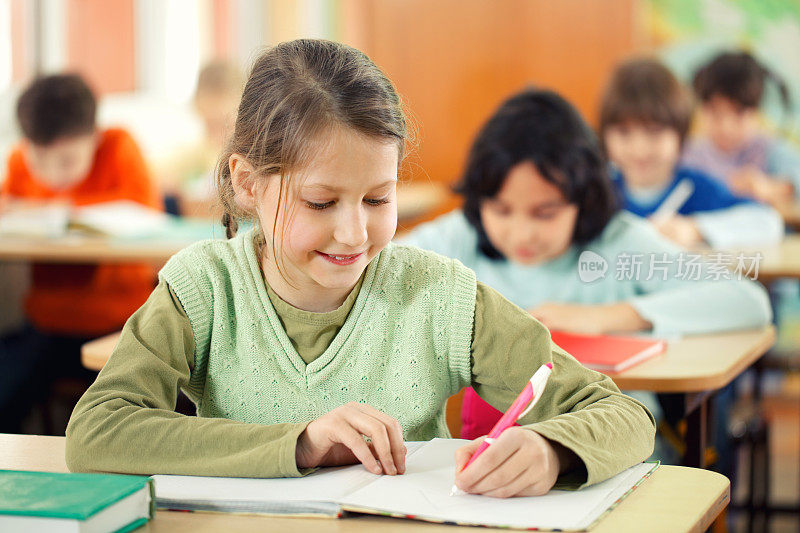 微笑的小学生在教室里写作。