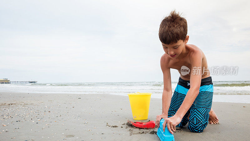 小男孩在沙滩上玩沙玩具时注意力集中
