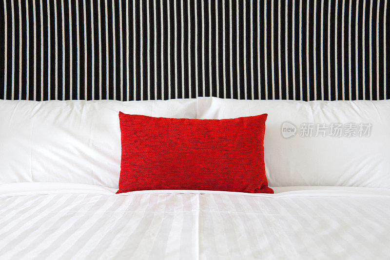 现代酒店房间的床上有清爽的床单和红色垫子
