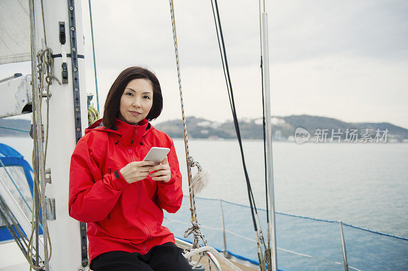 成熟的女人在游艇上使用智能手机