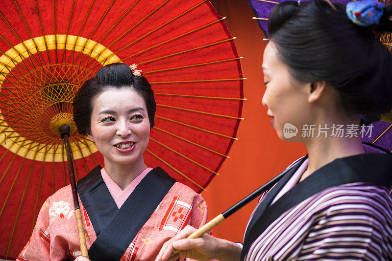 两个拿着雨伞的女人在谈论一个古老的日本