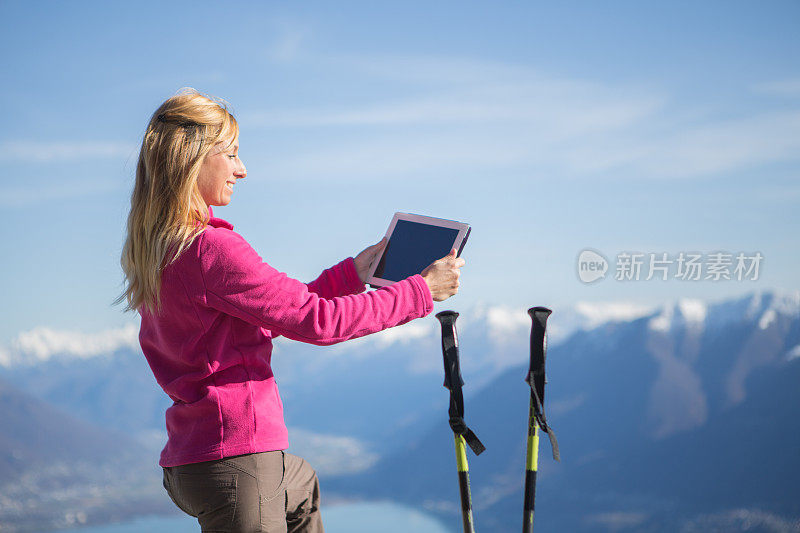 快乐的女人在山顶使用数字平板登山