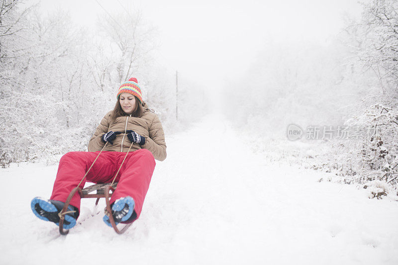 年轻女子在深雪中玩雪橇