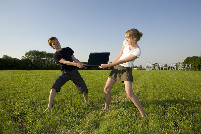 一个十几岁的女孩和一个男孩在为一台手提电脑争吵。