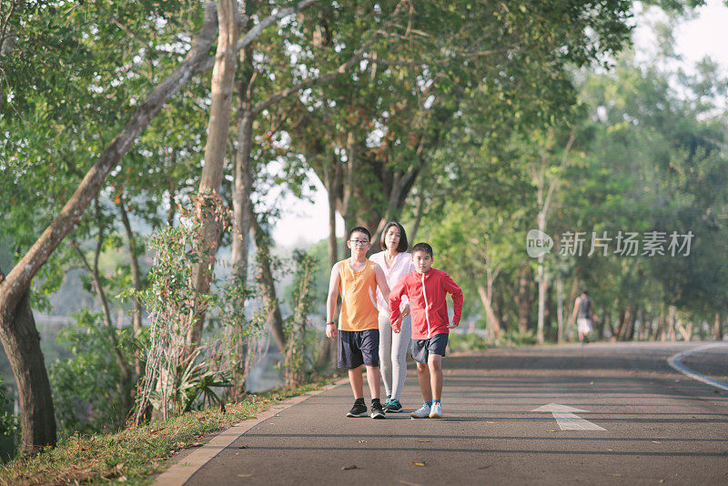 家庭运动快乐活跃的母亲和孩子在户外慢跑，在森林里跑步