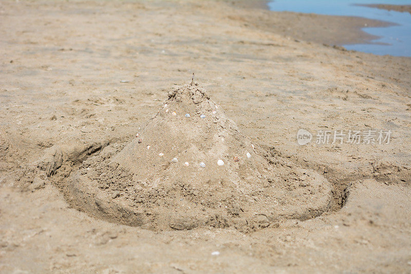 沙滩上的沙堡和空护城河等着被淹没