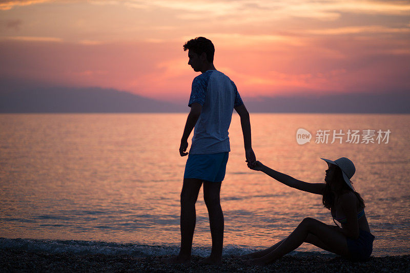 日落时分，一对情侣在海滩上剪影分手