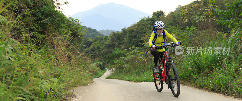 女自行车手在森林小径上骑山地车