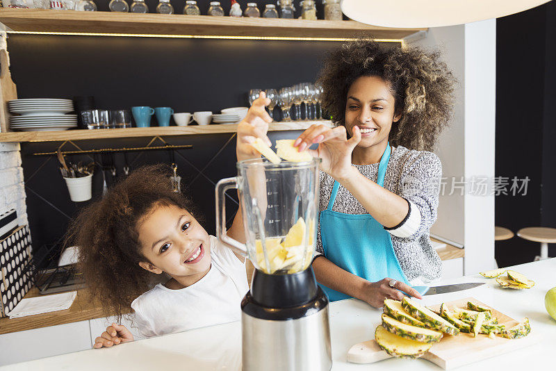 美丽的非洲裔美国妇女和她的女儿在厨房切水果