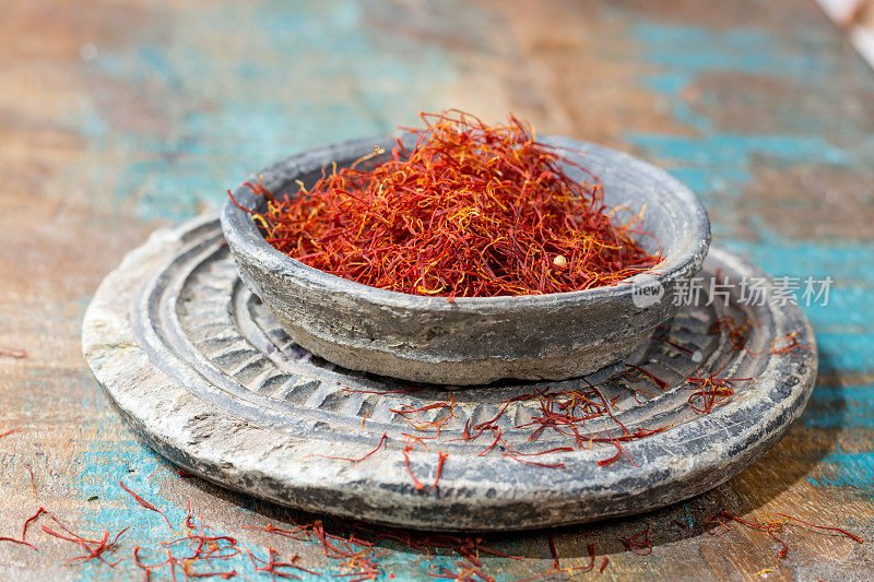 干燥的有机红藏红花香料在一个石头碗在木制的背景