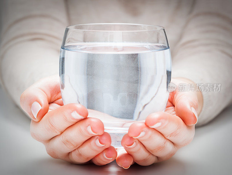 一杯干净的矿泉水在女人的手中。32、环保健康饮品。