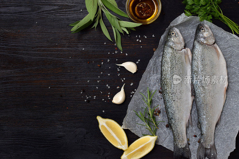 两块河鳟鱼放在木板上，配上香草、香料、柠檬和胡椒，准备烹饪。新鲜的鱼
