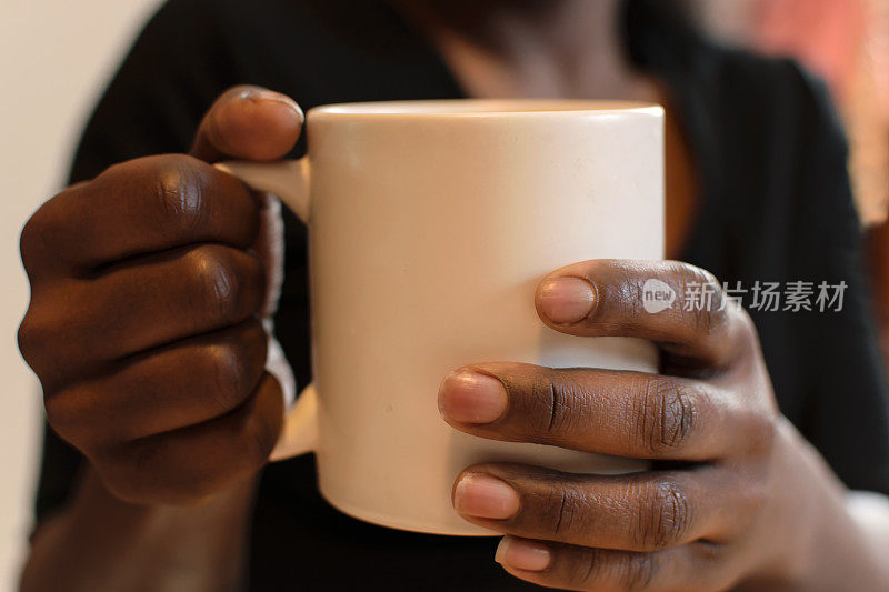 一个非裔美国女人早上拿着一个咖啡杯
