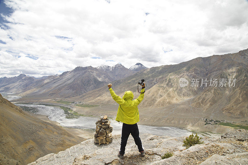 成功的摄影师手持单反相机在山上