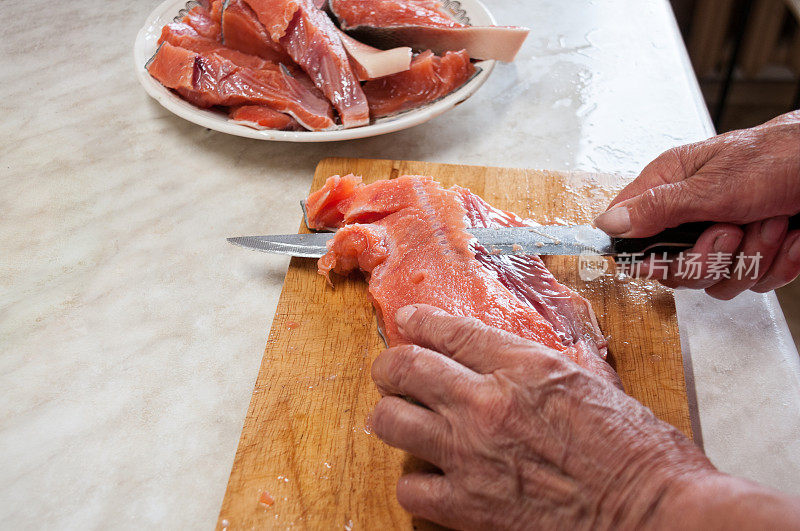 女人的手在厨房里切着红色的鱼