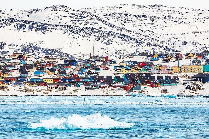 格陵兰岛伊卢利萨特的北极雪城全景，在冰雪覆盖的岩石山上有色彩斑斓的因纽特人的房子