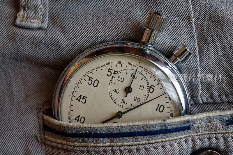 古董秒表，在灰色牛仔布的口袋里用蓝色线，测量时间的价值，旧式时钟的箭头分，秒精确计时记录