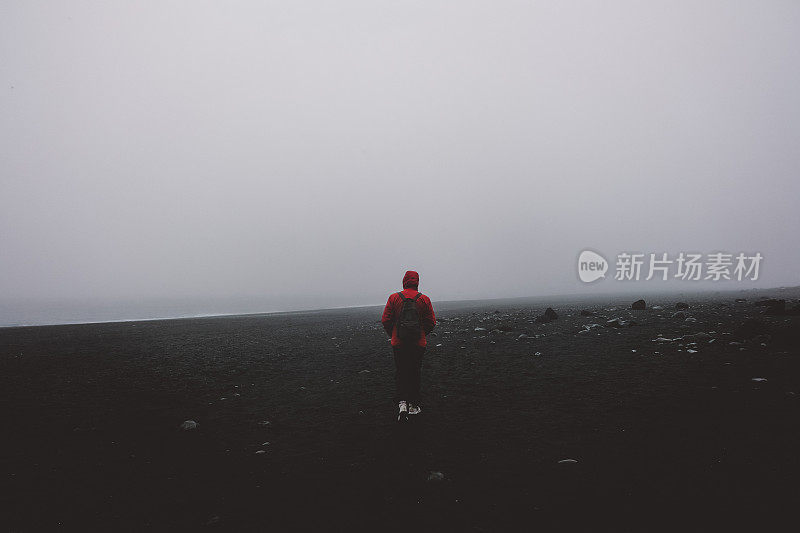 冰岛黑沙滩上的红衣男子