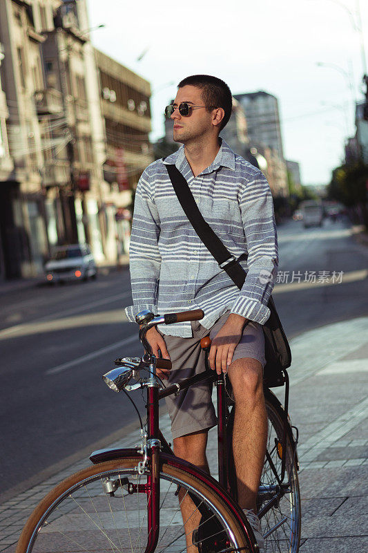 时髦的男人在城市的街道上骑自行车