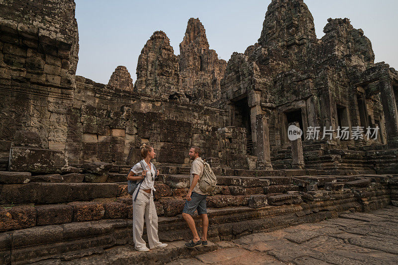 一对在亚洲旅游的游客，在夕阳下凝视美丽的古庙和古老的废墟;人发现探索理念