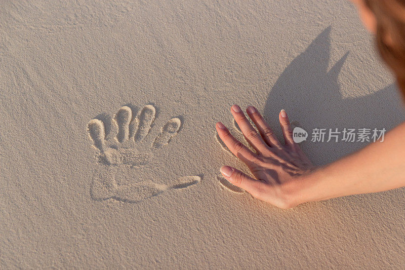 年轻女子在白沙上做手印