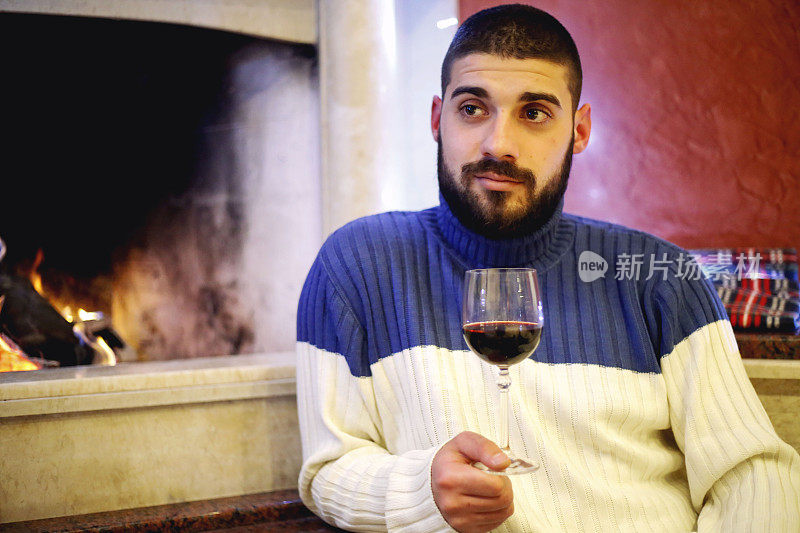 男人喝着红酒，在壁炉旁休息。