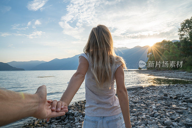 跟着我的概念-金发女友牵着男人的手到美丽的湖和山的环境