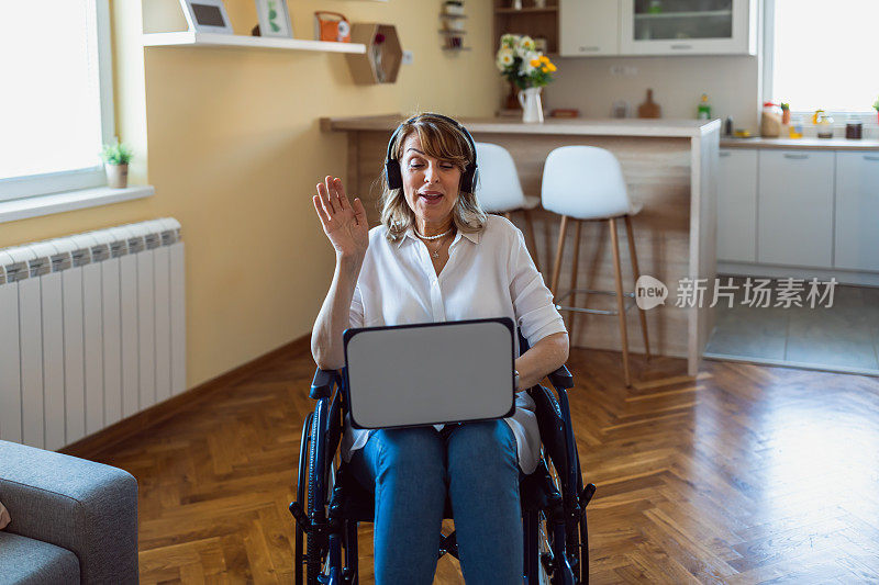 快乐的成熟女人在轮椅上与家人视频通话在家里挥手