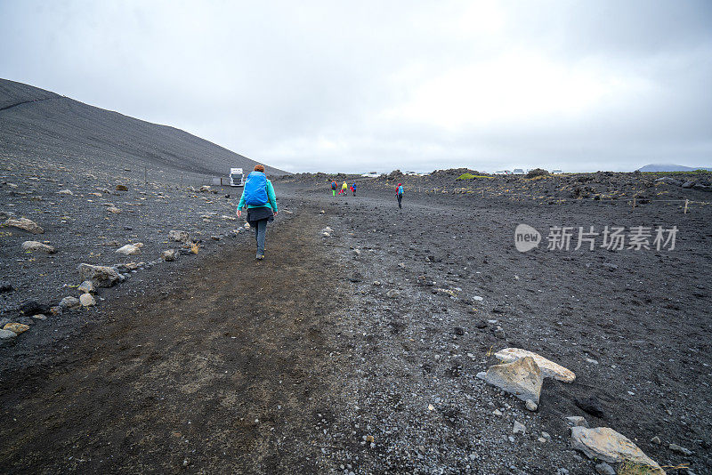 游客们从冰岛北部的赫弗哈尔火山口徒步到后台的停车场。