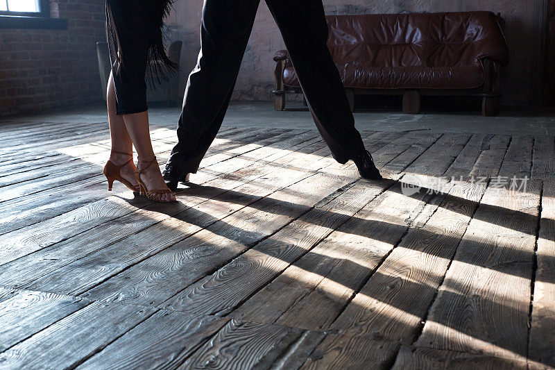 两名专业交际舞演员的两条腿在阁楼工作室跳舞。美丽的艺术表演与浓重的烟雾。运动生活的概念。激情和情感的舞蹈。