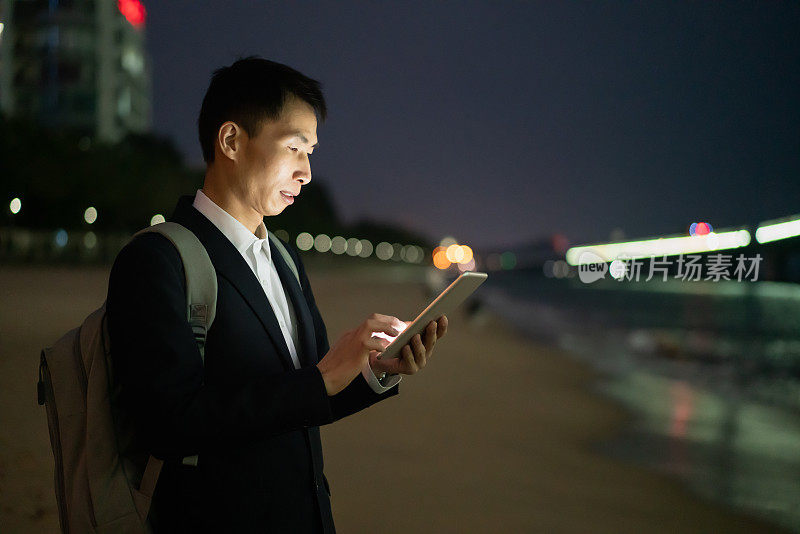 一名亚洲男子在海边使用智能手机