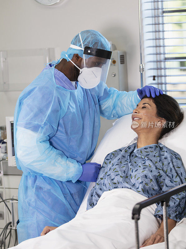 穿着个人防护装备的男护士在病床上照顾病人