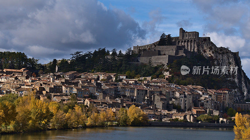 法国普罗旺斯小镇Sisteron的城市风景，著名的城堡坐落在岩石上，历史悠久的建筑和杜兰斯河在前面被五彩缤纷的树木环绕。