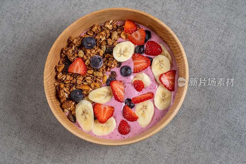 水果奶昔碗，里面有新鲜的浆果，香蕉，草莓，坚果，种子和自制的格兰诺拉麦片，这是健康的素食早餐