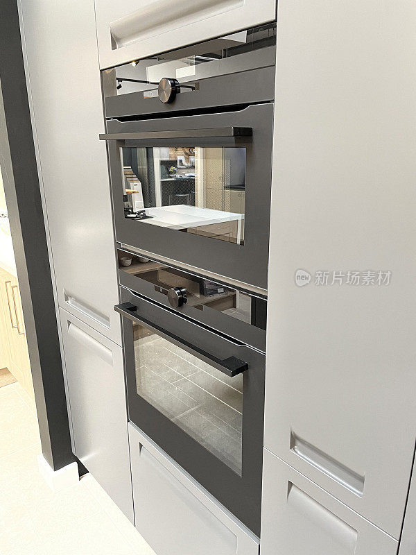 现代家庭厨房内置电蒸汽双烤箱玻璃门特写，聚焦前景