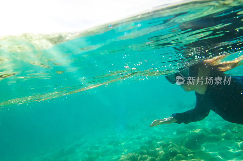 女孩在水晶蓝色的海中游泳，水下有珊瑚礁和海洋生物，浮潜加勒比海