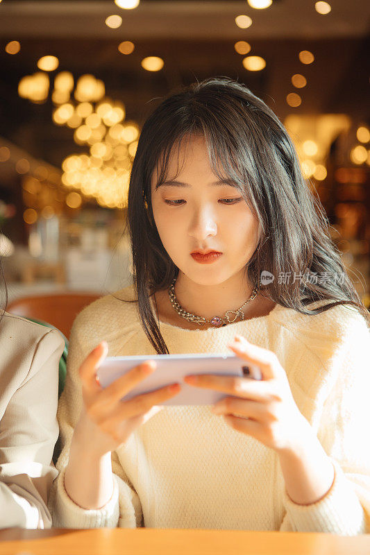 一位亚洲女性在咖啡店玩手机游戏