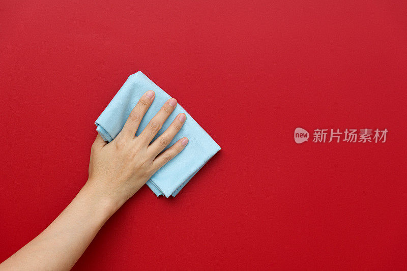 女人用抹布手工清洁红墙