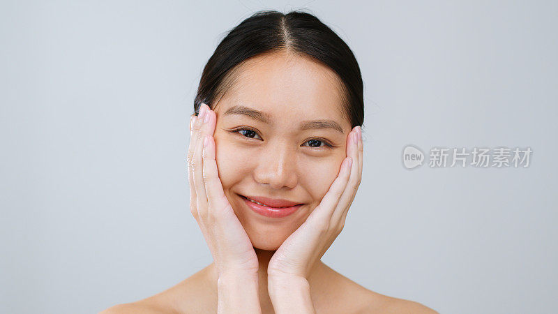 肖像年轻的亚洲美女触摸健康的身体皮肤在灰色的背景，亚洲美容皮肤的概念