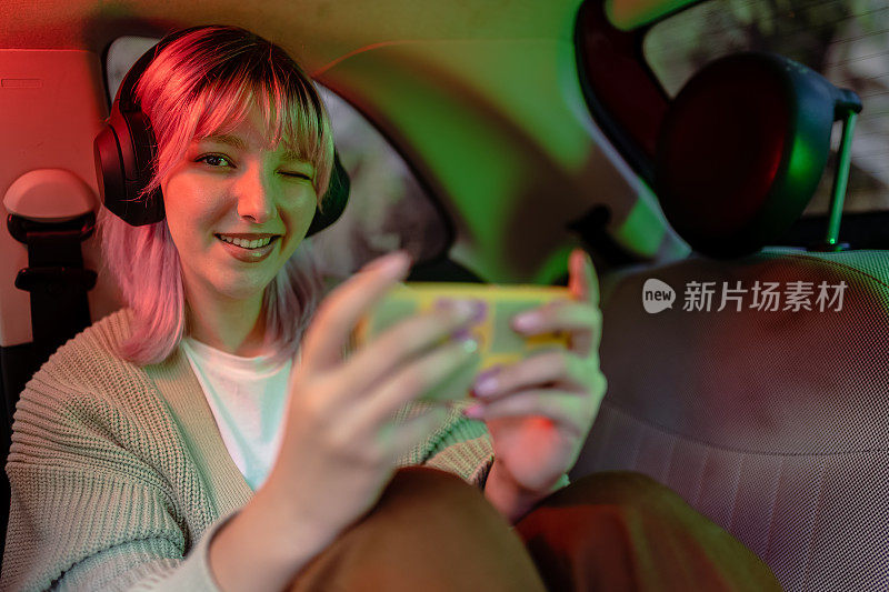 漂亮的女孩在出租车上玩电子游戏