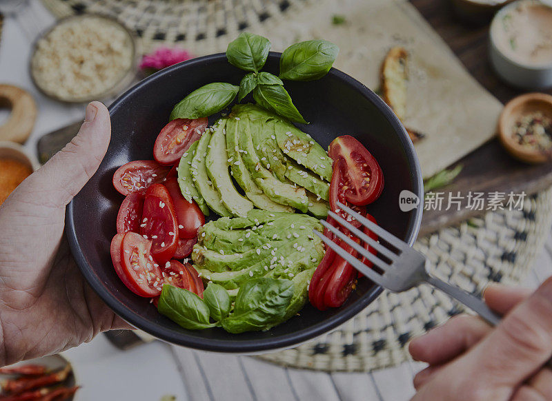 一个男人正在用陶瓷盘子吃素食沙拉