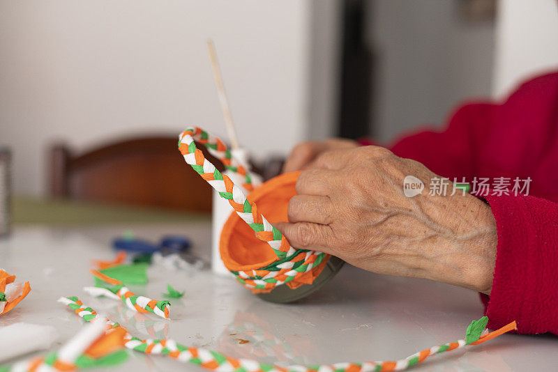 一位老妇人的手正在用材料制作工艺品