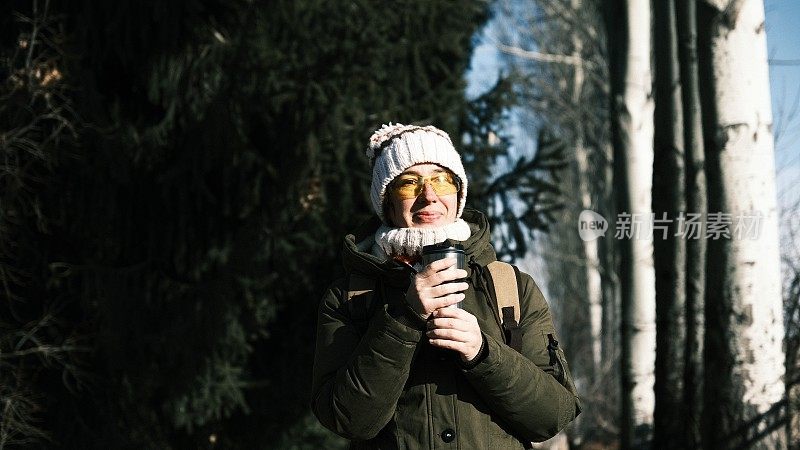 女游客正在用旅行杯喝热饮