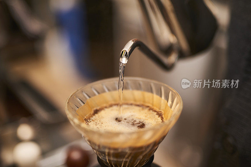 年轻的亚洲咖啡师正在煮现磨咖啡。