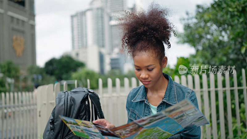 年轻的非裔美国女游客在公园看城市地图