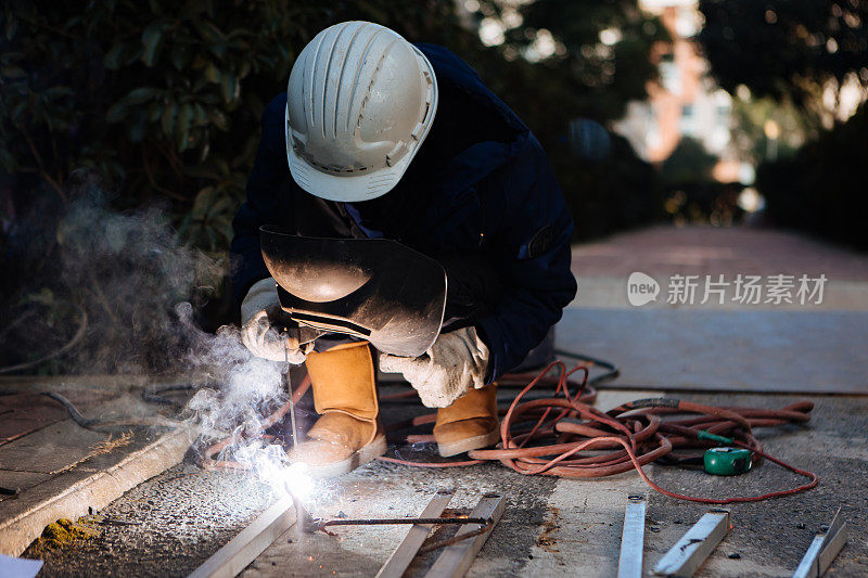 一名中年男性工人正在使用切割机和焊机