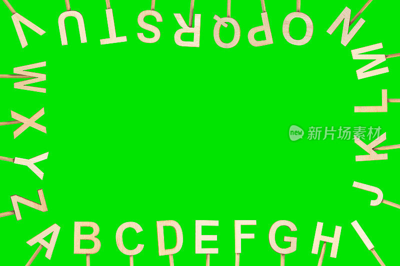 木制字母在屏幕周围形成字母表，中间有空余空间。绿色色度背景。