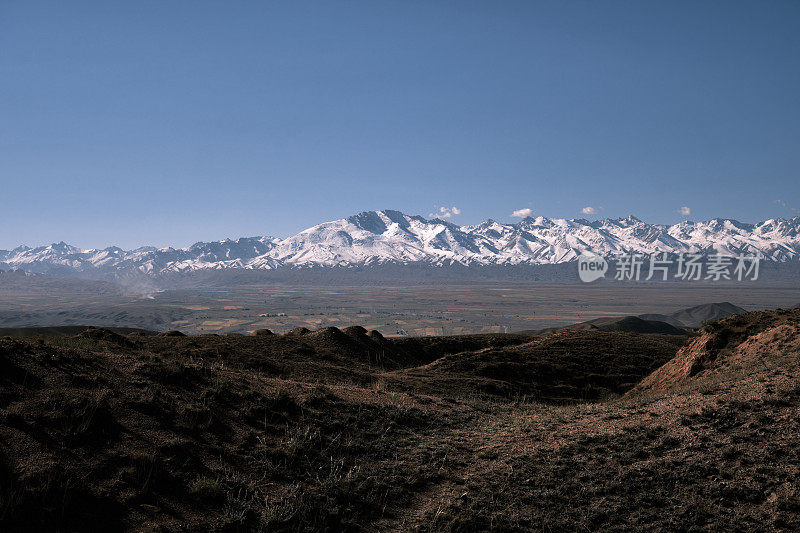 积雪覆盖的山脊在较低的山脉后面。南天山，贾拉拉巴德地区，吉尔吉斯斯坦